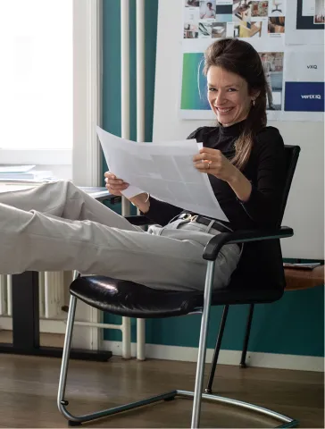 Natascha Müller-Kuhn sitzt im Bürostuhl und lacht in die Kamera